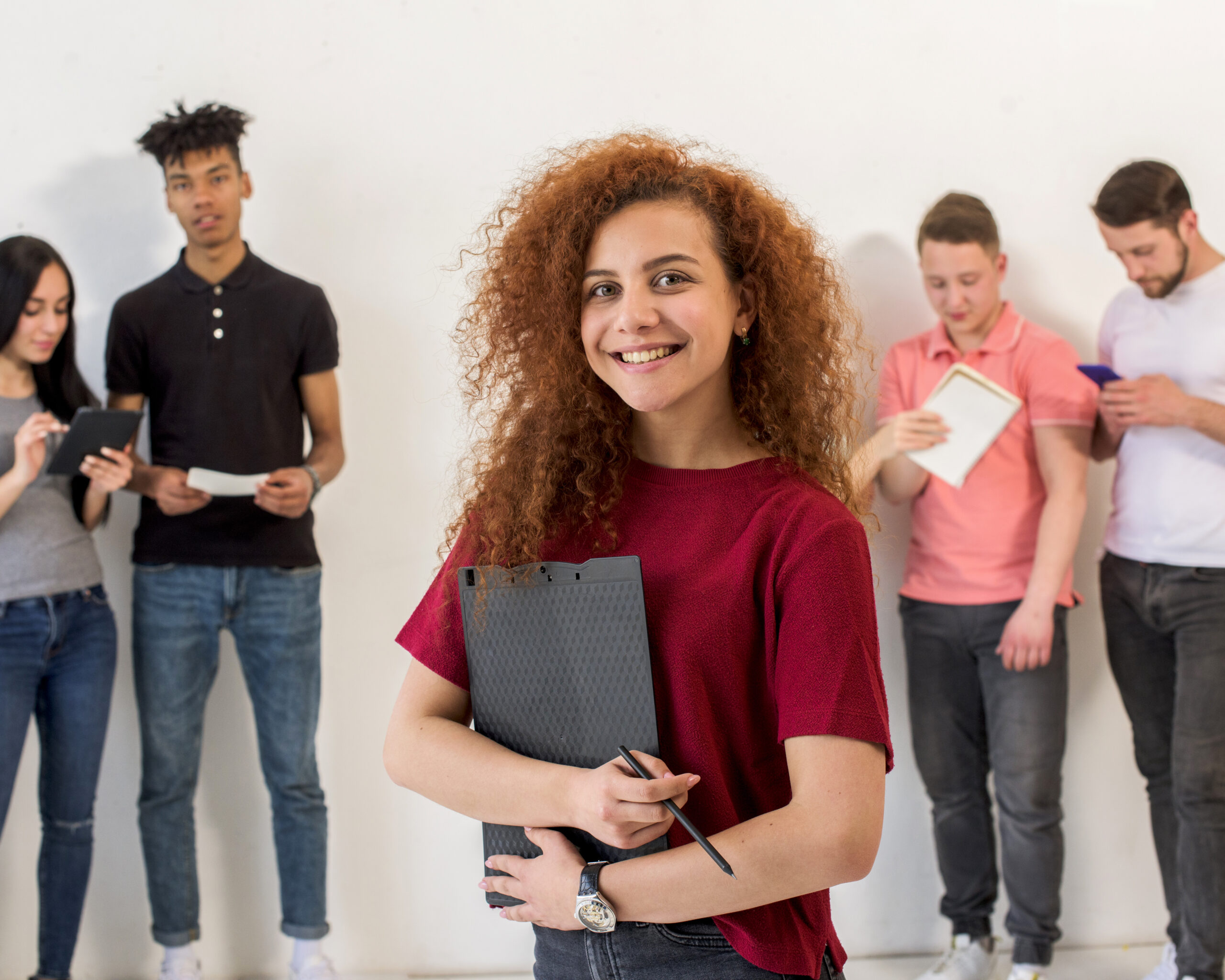 portrait happy young woman looking camera holding clipboard pencil front her friends