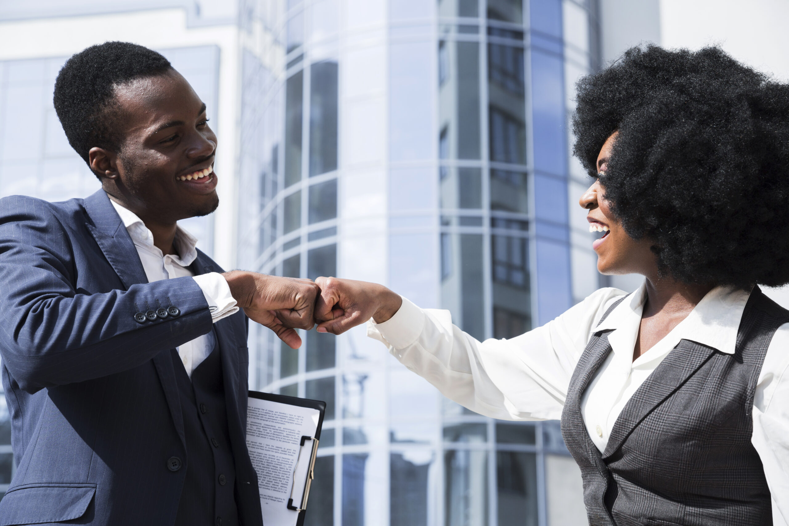 businessman businesswoman bumping their fist front corporate building