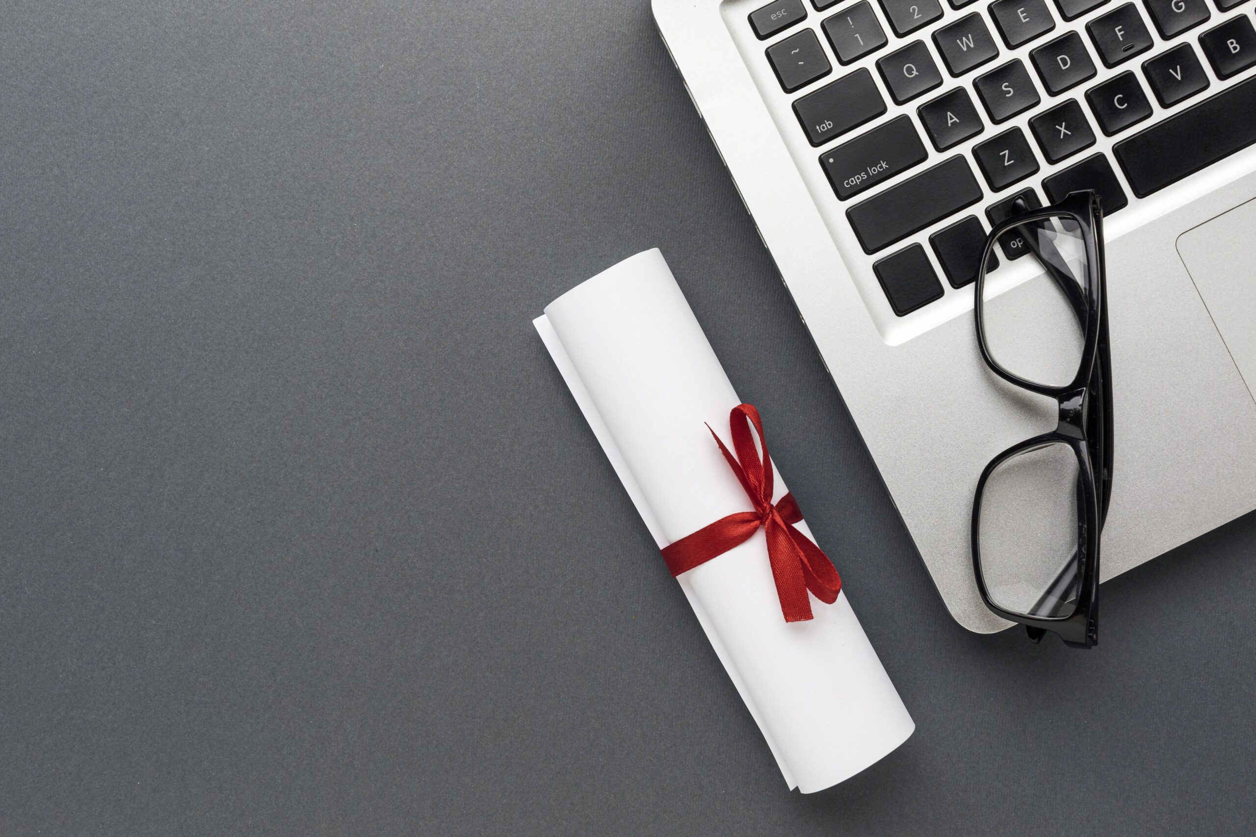 top view laptop with glasses diploma